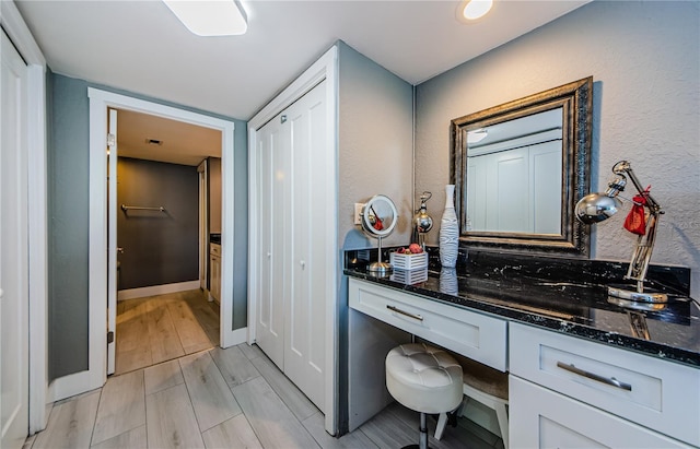 bathroom featuring vanity, a textured wall, baseboards, and wood tiled floor