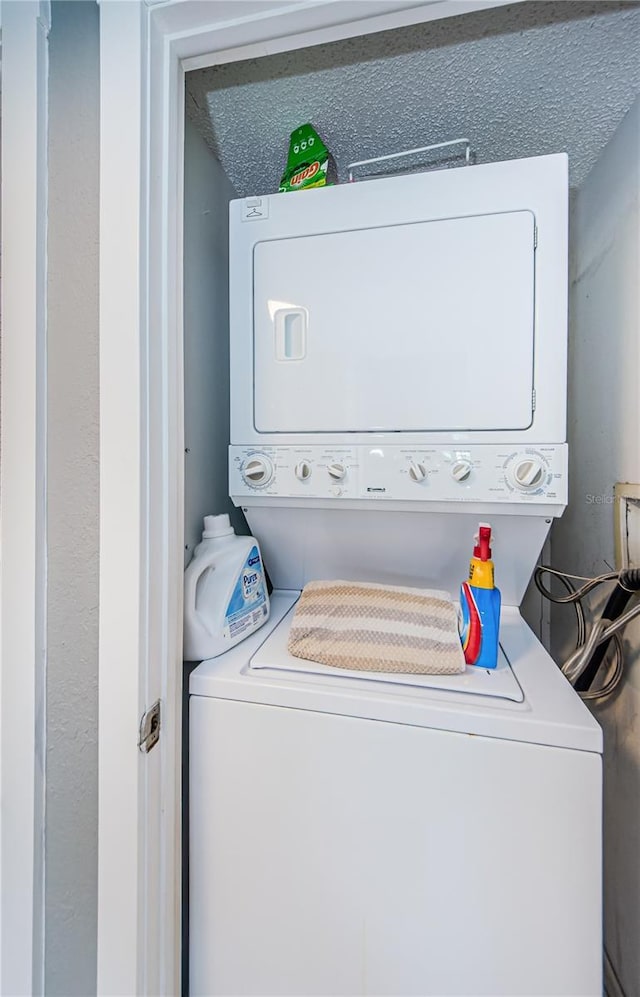 washroom with stacked washer / dryer and a textured ceiling