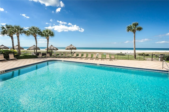 pool featuring a patio area, a water view, and fence