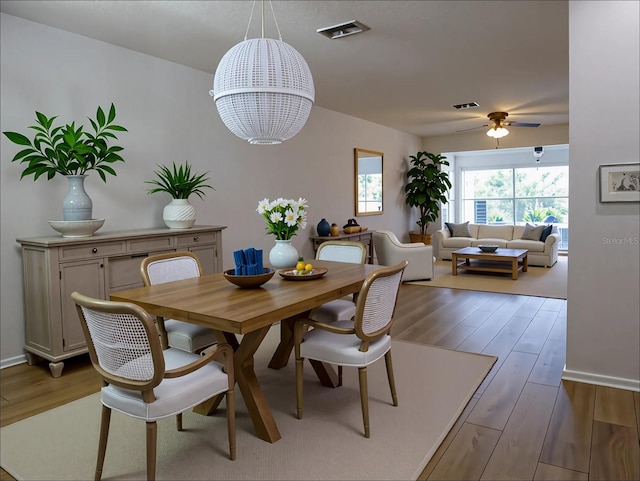 dining area featuring visible vents, wood finished floors, and ceiling fan with notable chandelier