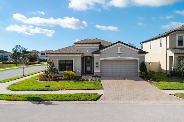 view of front of property featuring a front lawn, decorative driveway, an attached garage, and stucco siding