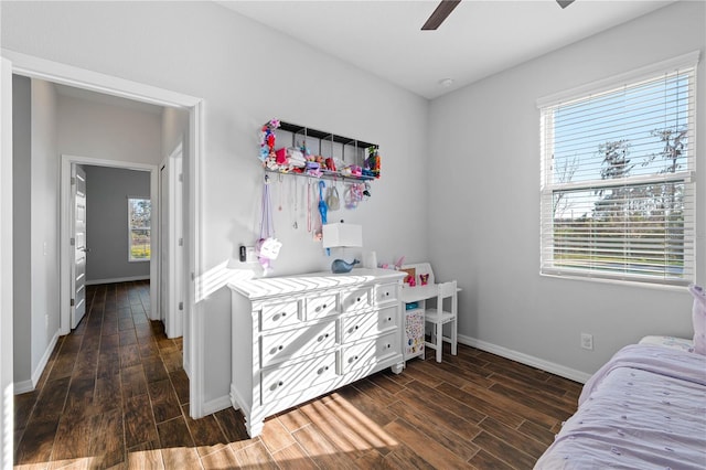 bedroom with dark wood-type flooring, a ceiling fan, and baseboards