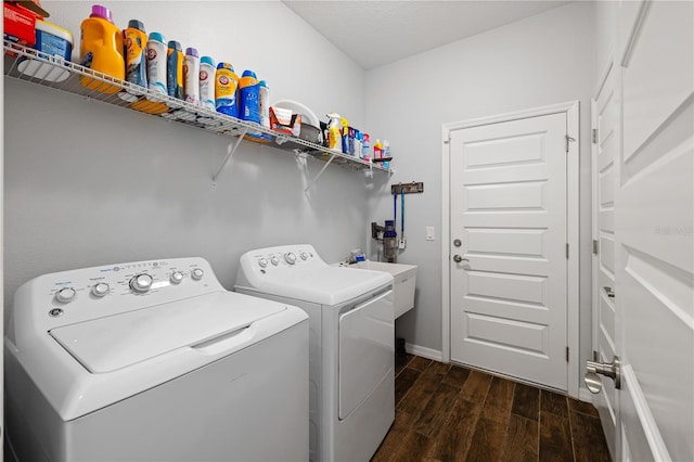 laundry room with laundry area, baseboards, dark wood-style floors, washing machine and clothes dryer, and a sink