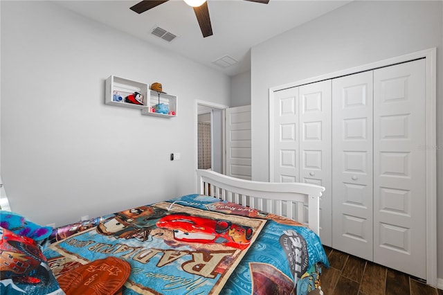 bedroom featuring a closet, dark wood-style flooring, visible vents, and ceiling fan