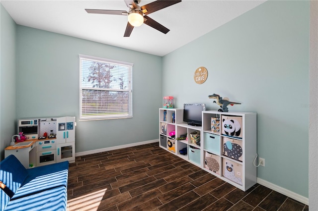 recreation room with wood finish floors, a ceiling fan, and baseboards