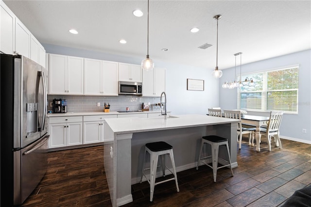 kitchen with tasteful backsplash, visible vents, dark wood-type flooring, stainless steel appliances, and light countertops