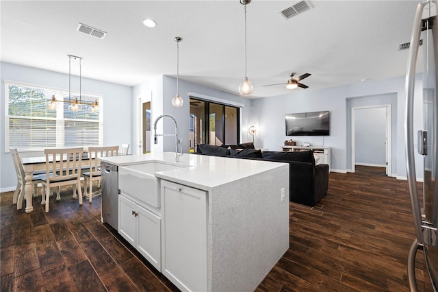 kitchen with dark wood-style flooring, a sink, visible vents, hanging light fixtures, and stainless steel dishwasher