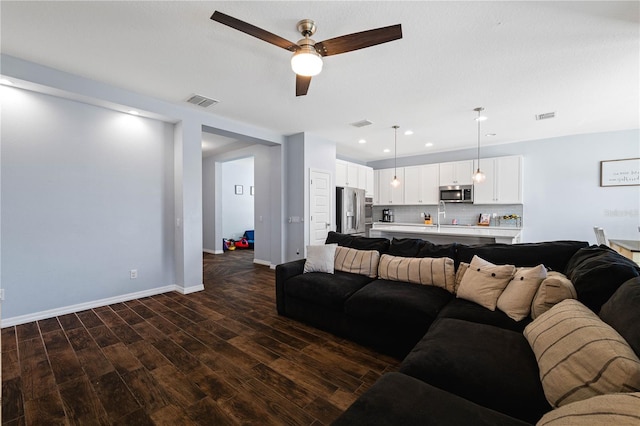 living room with baseboards, visible vents, dark wood finished floors, and recessed lighting