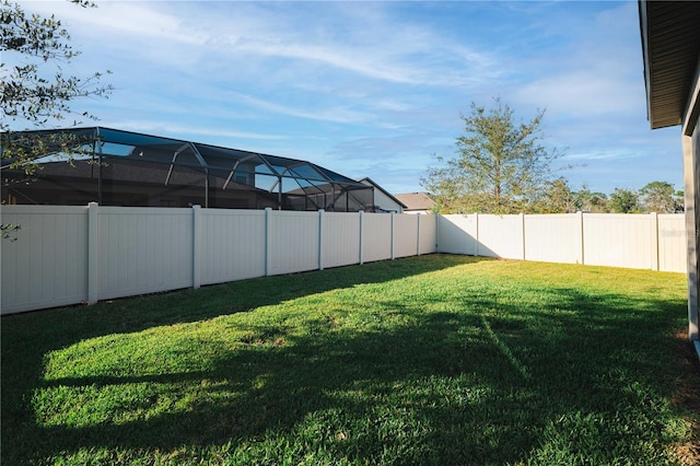 view of yard with glass enclosure and a fenced backyard