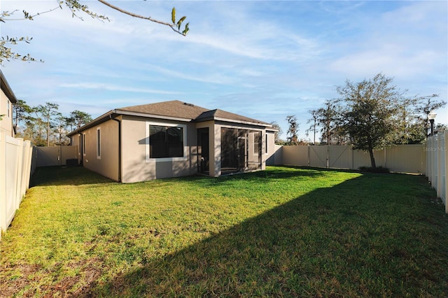 rear view of property with a fenced backyard, a lawn, and stucco siding