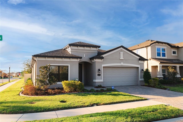 view of front facade featuring a garage, a front yard, decorative driveway, and stucco siding