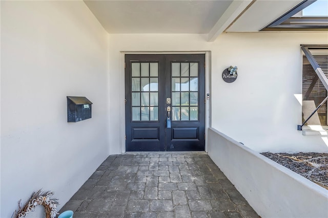 doorway to property featuring french doors and stucco siding