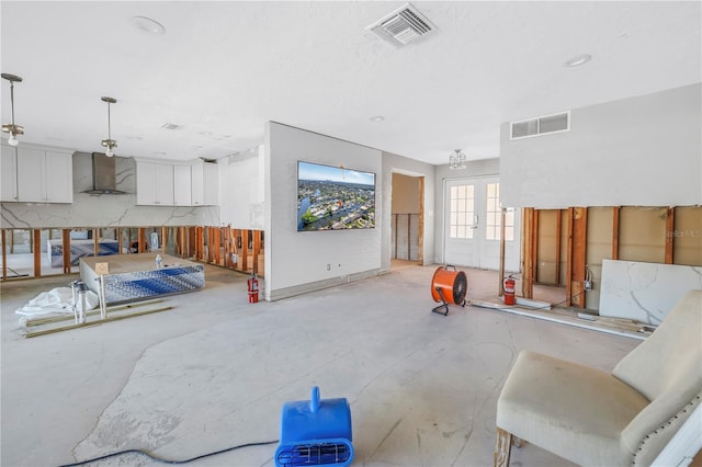 living area featuring french doors, visible vents, and concrete floors