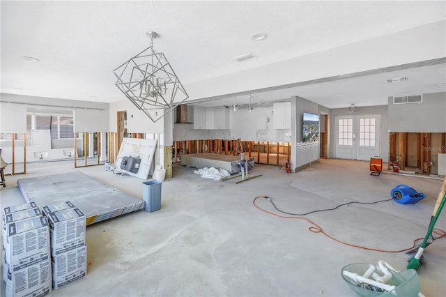 living room with french doors, unfinished concrete flooring, and visible vents