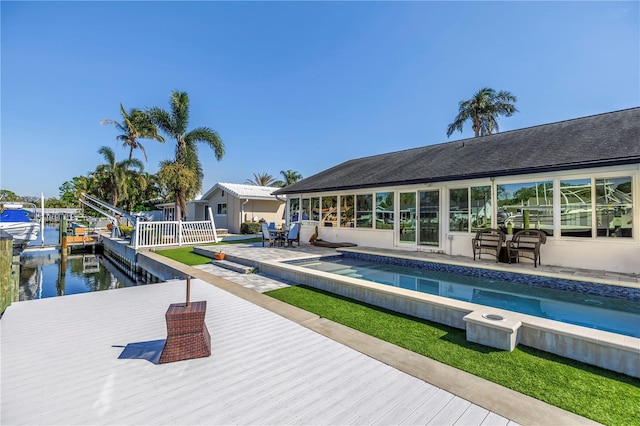 outdoor pool with a dock, a water view, boat lift, and fence