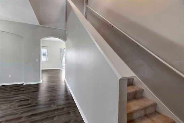 stairs featuring baseboards, arched walkways, and wood finished floors