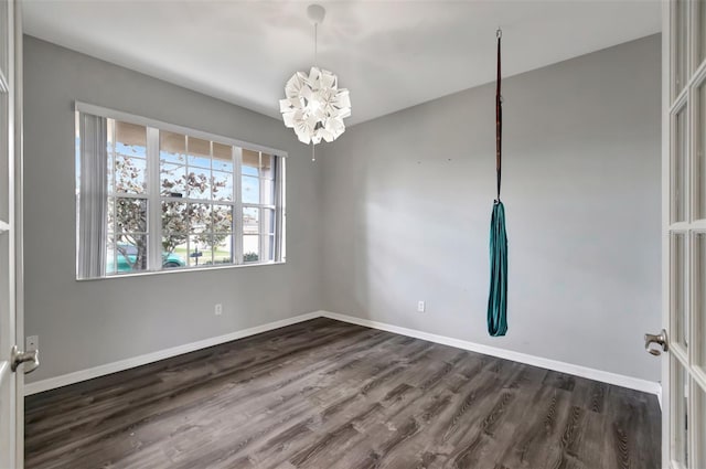 empty room featuring dark wood-style floors, baseboards, and an inviting chandelier