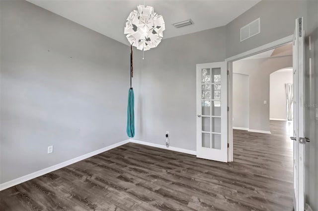 spare room with visible vents, arched walkways, dark wood finished floors, and baseboards