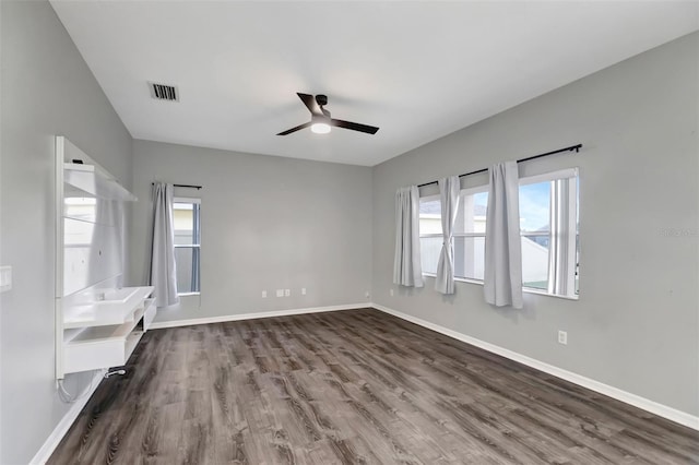 spare room featuring visible vents, dark wood finished floors, baseboards, and ceiling fan