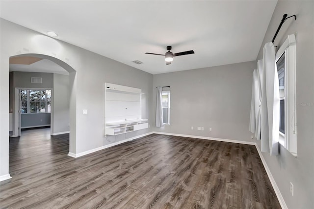 unfurnished living room with baseboards, visible vents, arched walkways, ceiling fan, and wood finished floors