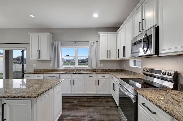 kitchen with light stone counters, recessed lighting, stainless steel appliances, a sink, and white cabinets