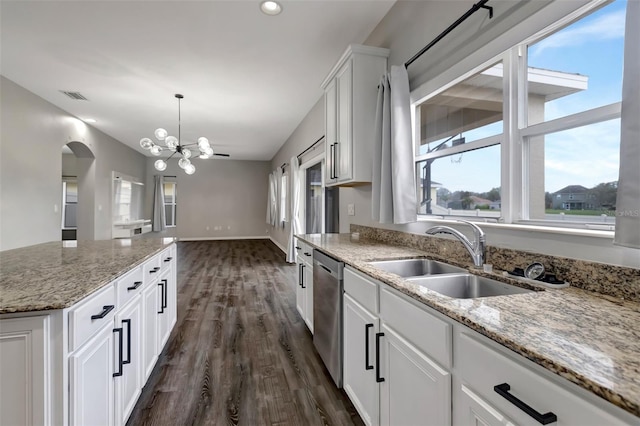 kitchen featuring arched walkways, visible vents, stainless steel dishwasher, a healthy amount of sunlight, and a sink