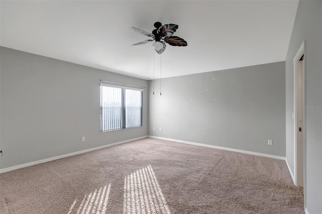 carpeted empty room featuring ceiling fan and baseboards