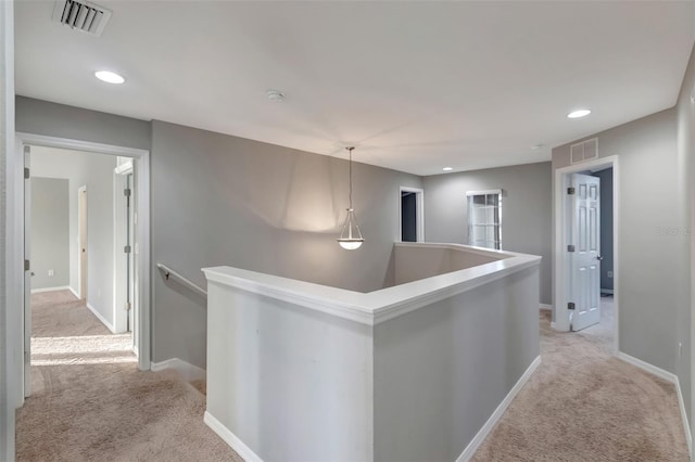 corridor with light carpet, visible vents, and an upstairs landing