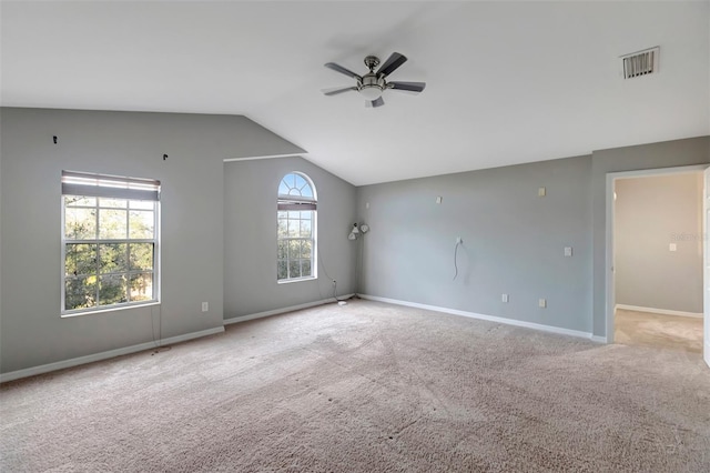 empty room featuring ceiling fan, visible vents, baseboards, vaulted ceiling, and carpet