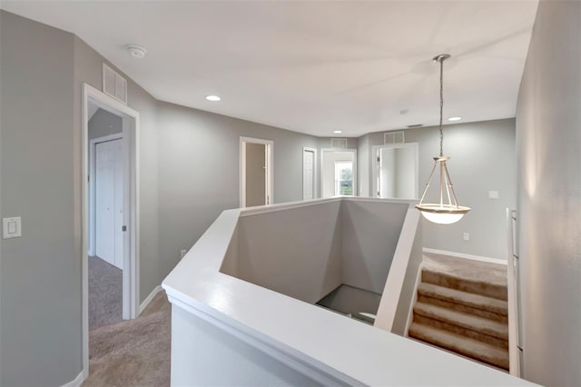 hall featuring light carpet, baseboards, and visible vents