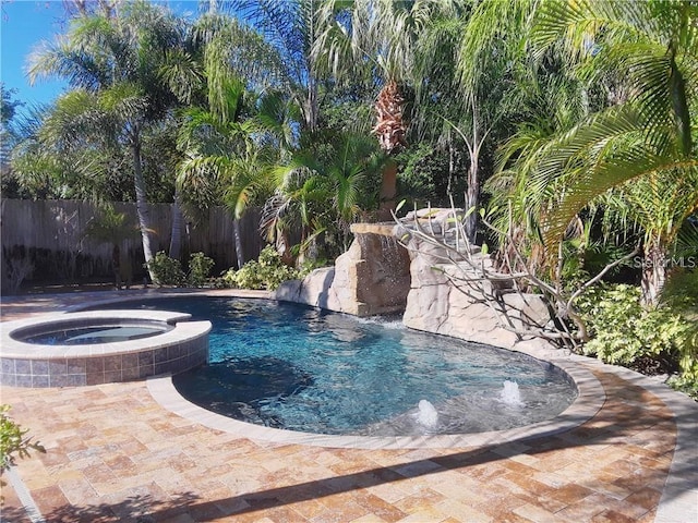 view of pool featuring a pool with connected hot tub and fence