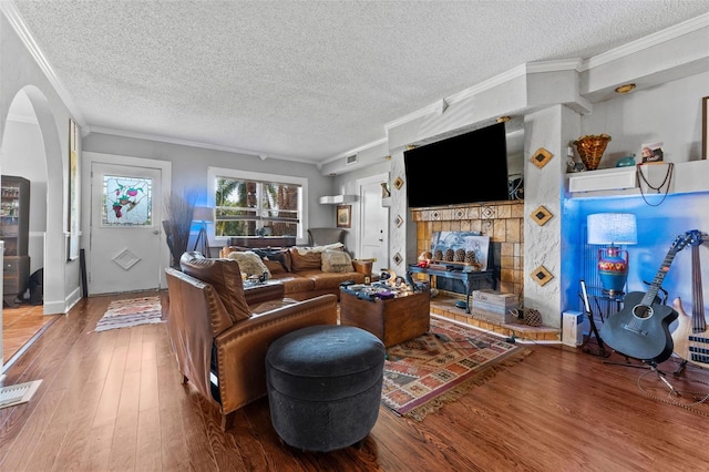 living room featuring arched walkways, wood finished floors, and ornamental molding