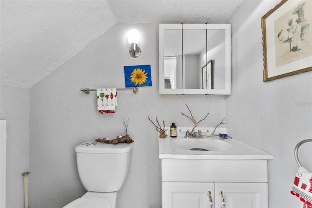 bathroom with lofted ceiling, toilet, vanity, and a textured ceiling