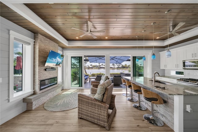 interior space with a sink, wood ceiling, a sunroom, a tray ceiling, and stainless steel microwave