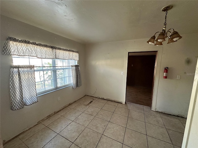 spare room featuring light tile patterned floors and a chandelier