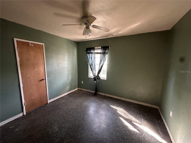 unfurnished room with ceiling fan and baseboards