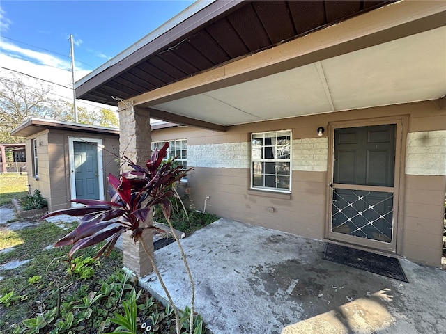 property entrance with concrete block siding and a patio