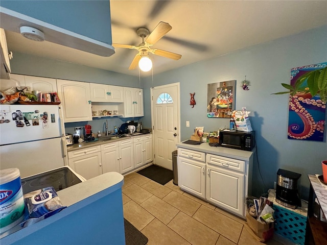 kitchen with a ceiling fan, freestanding refrigerator, white cabinetry, light tile patterned flooring, and black microwave