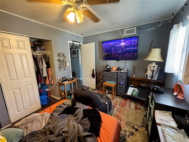 bedroom with a closet, wood finished floors, visible vents, and a ceiling fan