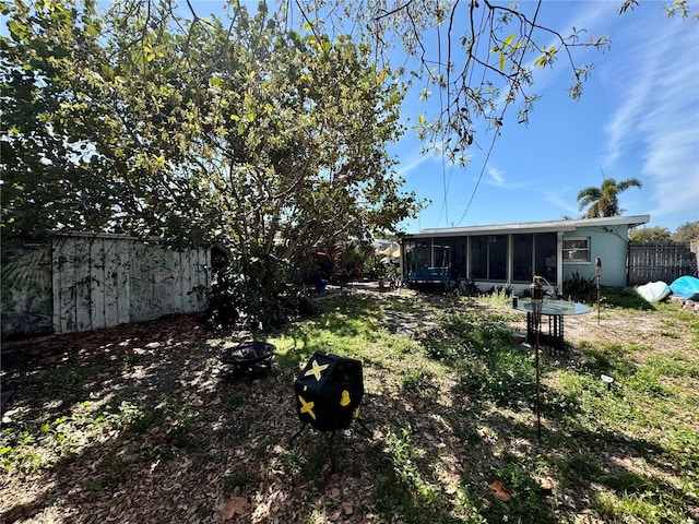 view of yard featuring an outdoor fire pit, a sunroom, and fence