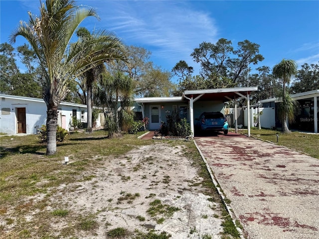 ranch-style home featuring aphalt driveway, an attached carport, and a front yard