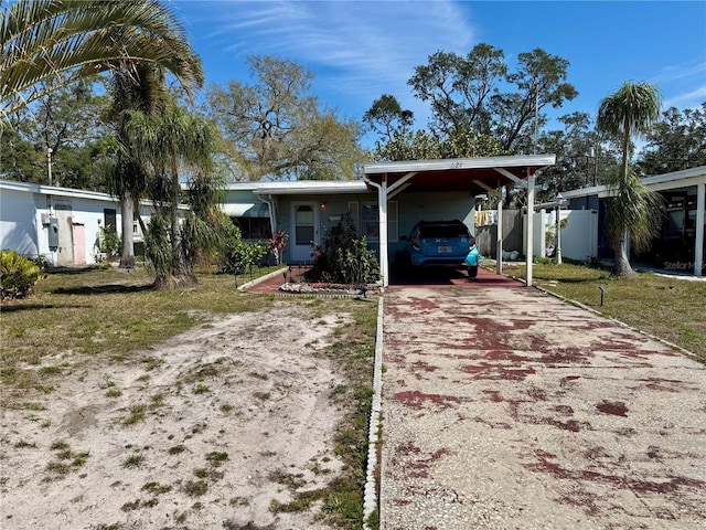 single story home featuring a carport, a front lawn, and concrete driveway