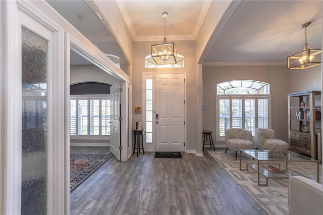 foyer featuring a chandelier, ornamental molding, wood finished floors, and a healthy amount of sunlight