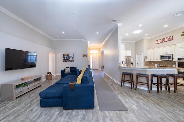 living area featuring light wood-type flooring, visible vents, arched walkways, and baseboards