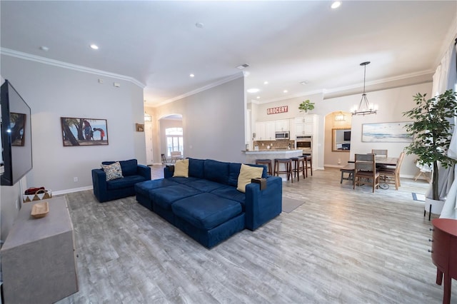 living room with arched walkways, a chandelier, baseboards, light wood-style floors, and ornamental molding