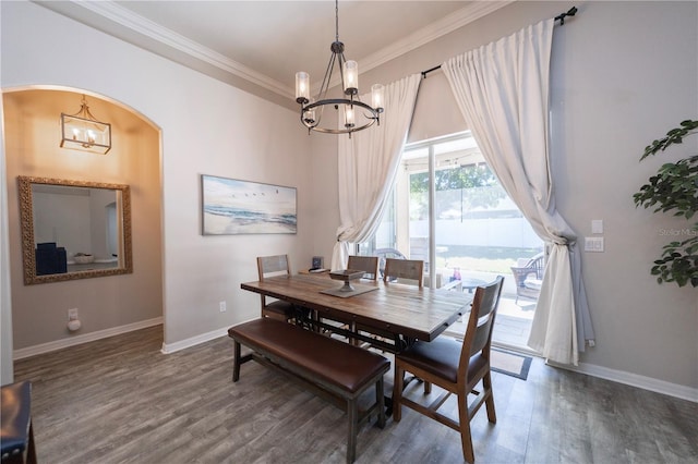 dining area with arched walkways, crown molding, an inviting chandelier, wood finished floors, and baseboards