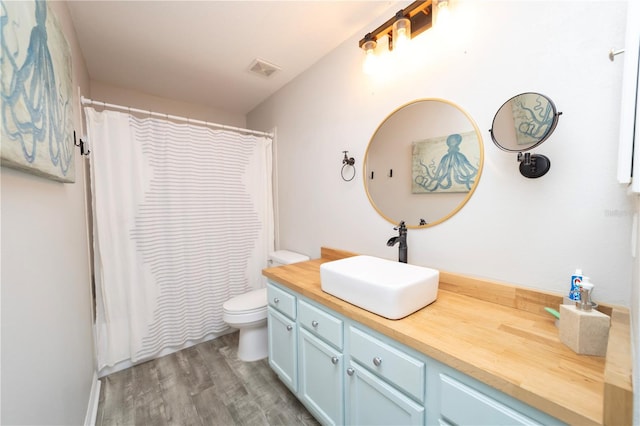 full bathroom featuring visible vents, a shower with shower curtain, toilet, wood finished floors, and vanity