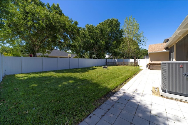 view of yard with a fenced backyard, central AC, and a patio