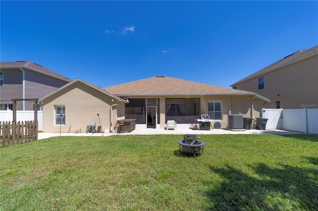 back of house featuring a fenced backyard, a fire pit, a sunroom, a yard, and a gate