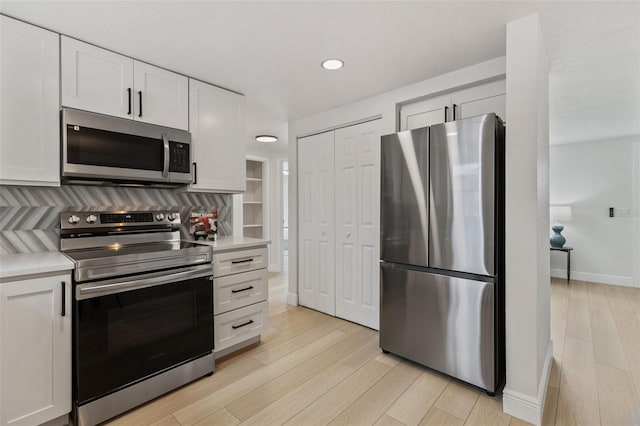 kitchen with white cabinets, light wood-style flooring, appliances with stainless steel finishes, and light countertops